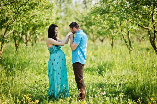 Happy pregnant couple at turquoise dress on the garden