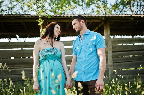 Happy pregnant couple at turquoise dress on the garden