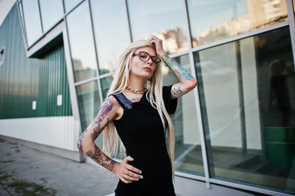 Young blonde tattoo girl background high-tech windows architectu