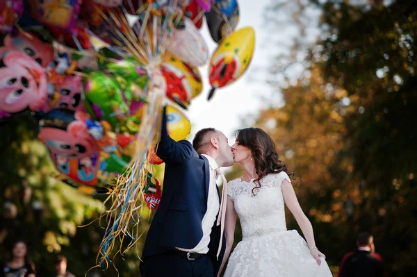 Wedding couple run in fun with balloons
