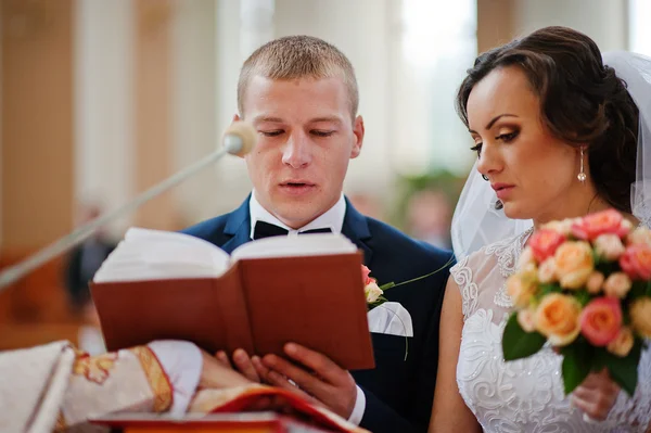 Newlywed give oath in church holding a bible