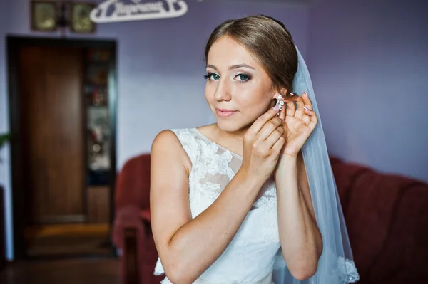 Cute young bride wear her earrings