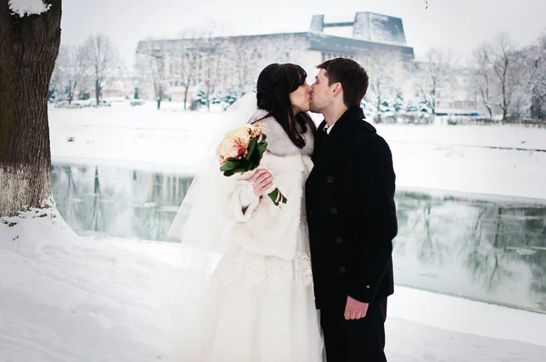 Wedding couple in winter snowly street background cold river
