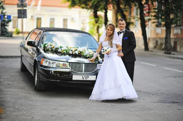 Wedding couple stay near black luxury limousine