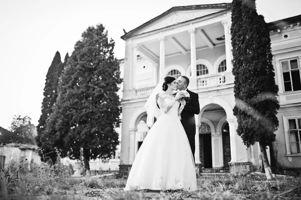 Stylish wedding couple near old vintage pink house with columns