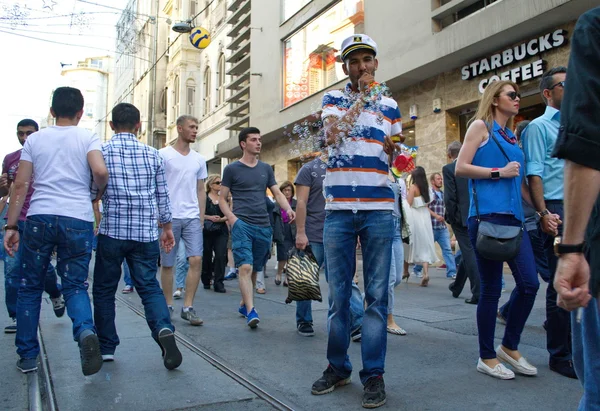 A man in a stripped shirt blowing bubbles in shopping street of Istanbul