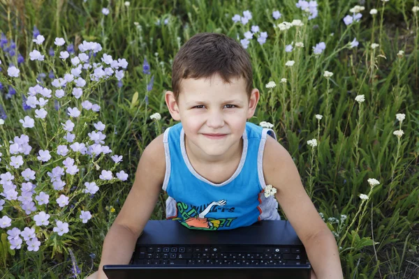 Little boy enjoys a laptop on nature