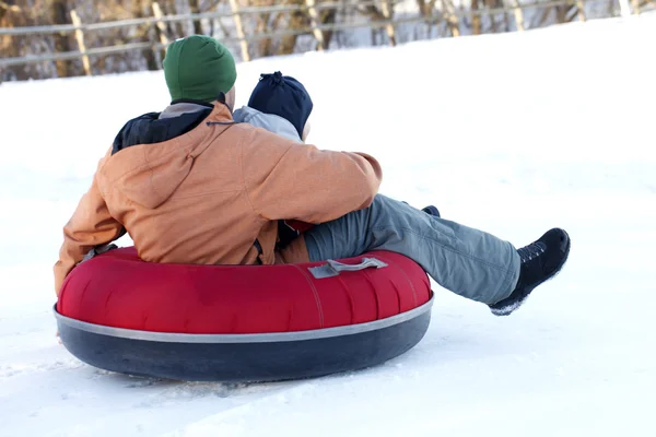Father with  young son riding on a snow tube