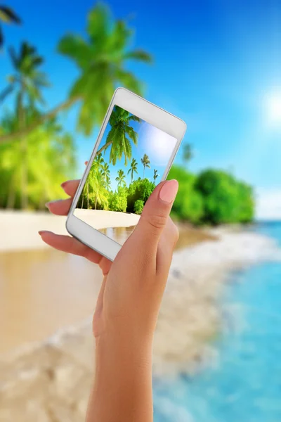 Close up hand holding smartphone on summer beach. technology, travel, tourism, communication and people concept
