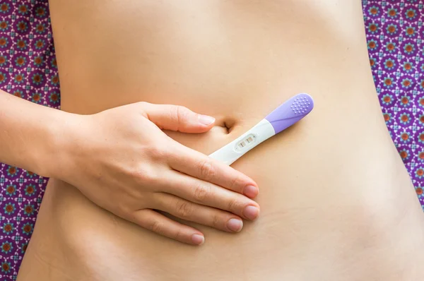 Pregnant woman holding positive pregnancy test