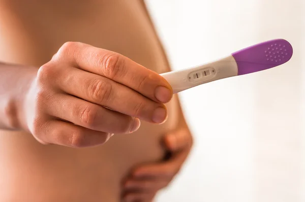 Pregnant woman holding positive pregnancy test