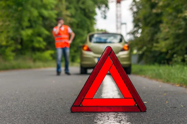 Broken car on the road and warning triangle