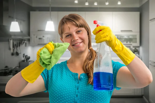 Young smiling housewife woman cleaning kitchen
