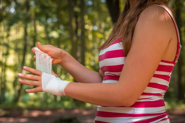 Woman applying bandage on her hand after injury
