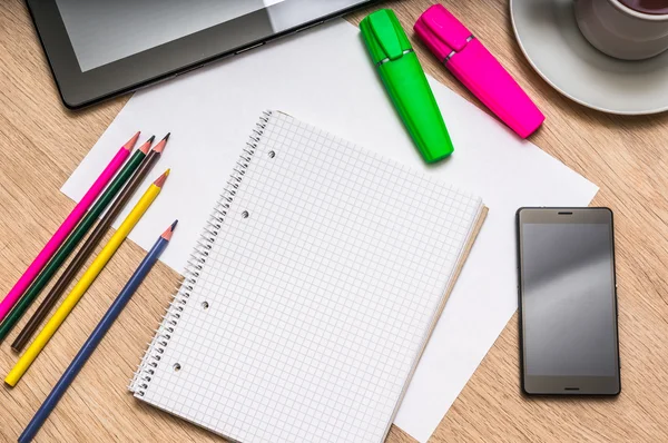 Notepad, mobile phone, paper, pencils and tablet on table