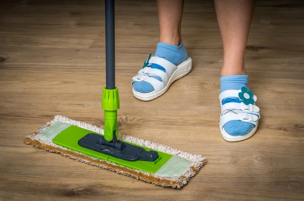 Woman with mop mopping wooden laminate floor