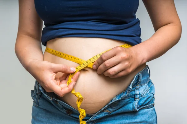 Overweight woman with tape measure around waist