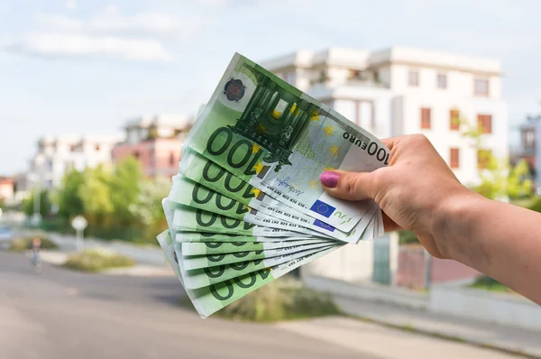 Property buyer holding euro banknotes and buying beautiful house