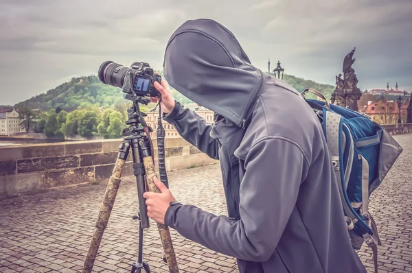 Photographer in hooded sweatshirt photographs of Charles Bridge