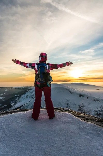 Girl watching at the sunset on the top of mountain