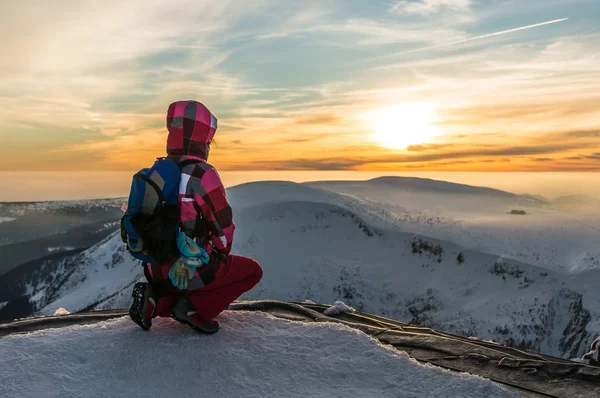 Girl watching at the sunset on the top of mountain