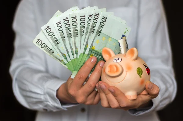 Young woman with piggy bank and euro money banknotes