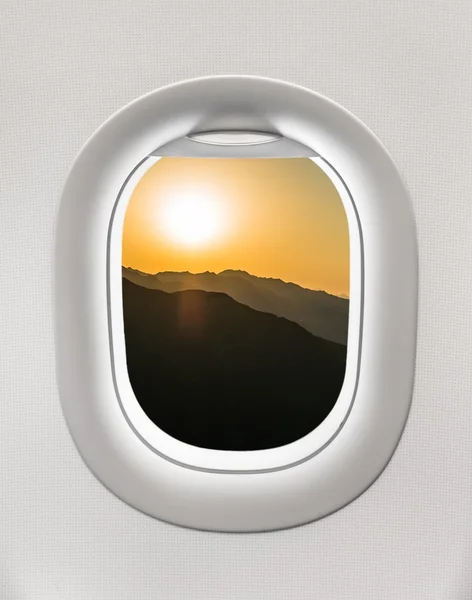Looking out the window of a plane to the mountains and sunset