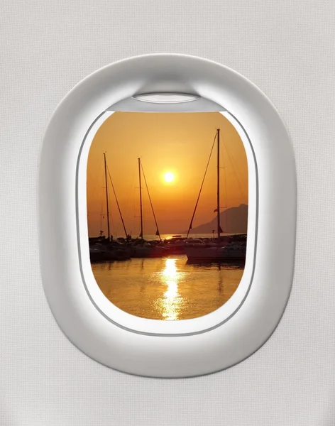 Looking out the window of a plane to the sunset in the harbor