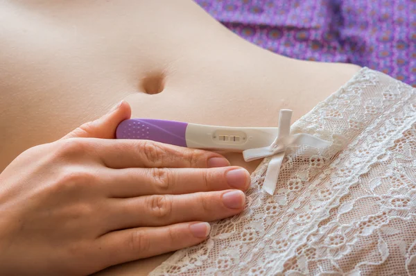 Pregnant woman holding positive pregnancy test