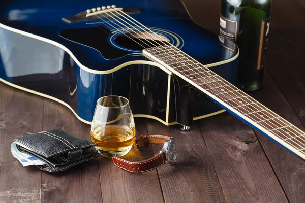 Guitar and whiskey on a wooden table