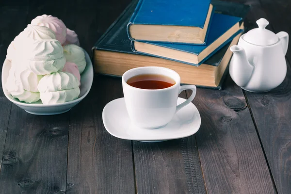 Evening with hot tea, sweets and books on wood table