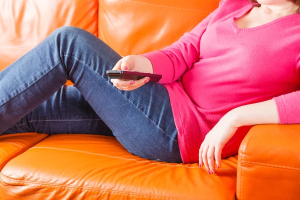 Woman sitting on sofa and swith TV channels