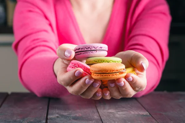 Macaroons colored in the hands of woman. French dessert. Close-u
