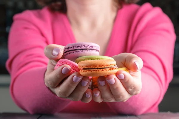 Macaroons colored in the hands of woman. French dessert. Close-u