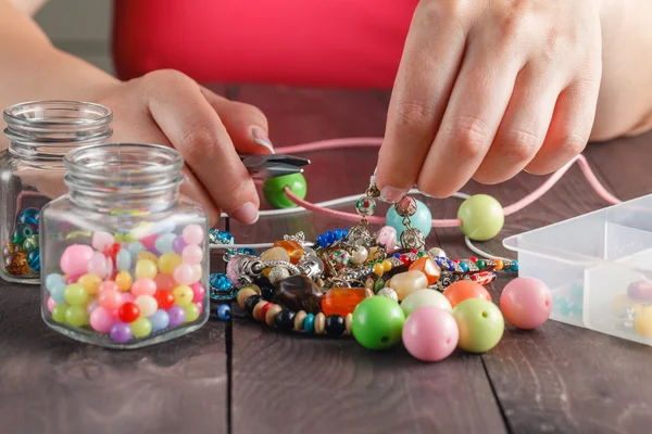 Woman making necklace from colorful beads