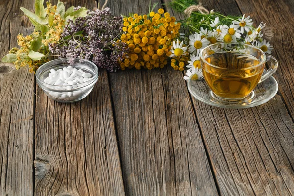Healing herbs and bowl of pills on wooden table