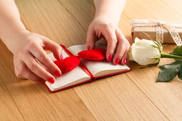 Female hands touch red heart on diary for Valentine's day with g