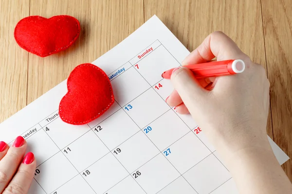 Close-up of woman highlighting date on calendar