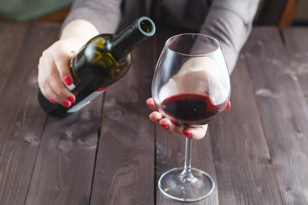 Alcoholic woman is pouring wine into a glass