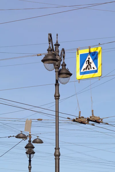 Street lamp, wires, street sign against blue sky