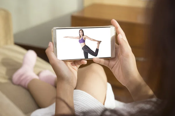 Beautiful woman playing phone on bed happily in morning. She watching the demonstration exercise through mobile phones. For women, health care and fitness It is important.