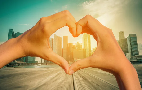 Vintage image of Heart Shaped Hand with blurred Singapore city skyline.