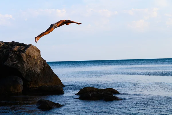 Man jumps from a cliff into the sea