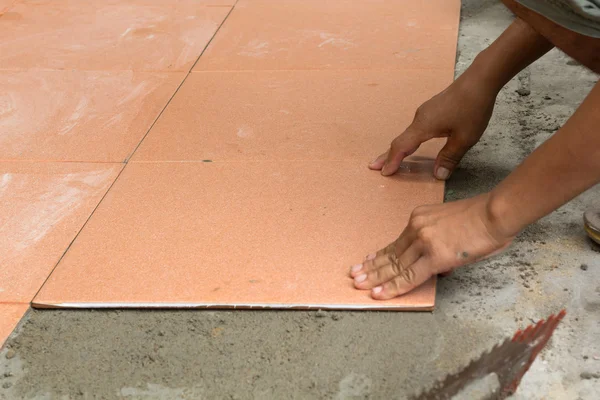 A plasterer is tiling at home, tile floor adhesive renovation at