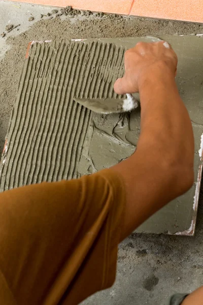 A tiler at work. bonding of floor tile with tile adhesive