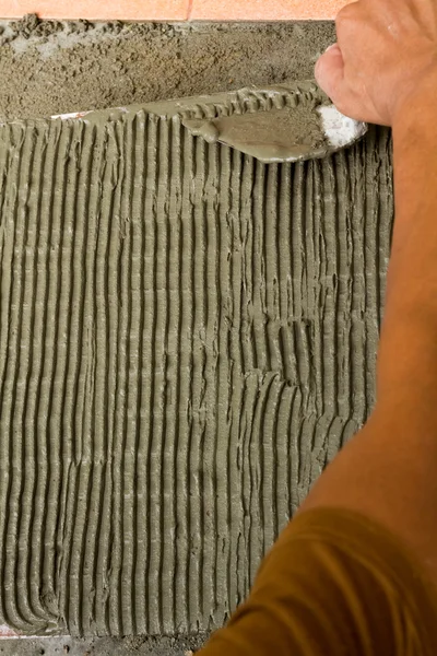 A tiler at work. bonding of floor tile with tile adhesive