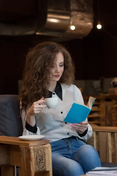 Beautiful girl with coffee reading a book in a coffee shop