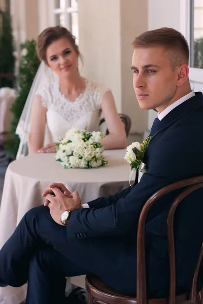 The groom looks at the camera while sitting at a table