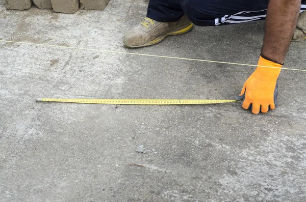 Construction worker takes measures for laying bricks of the wall