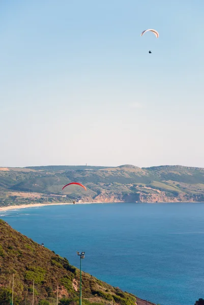 Two parachute flying in sardinian coast with sea and mountain be